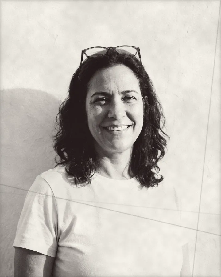 Portrait of a smiling woman with wavy brown hair and reading glasses pushed up on her head, printed for the wall