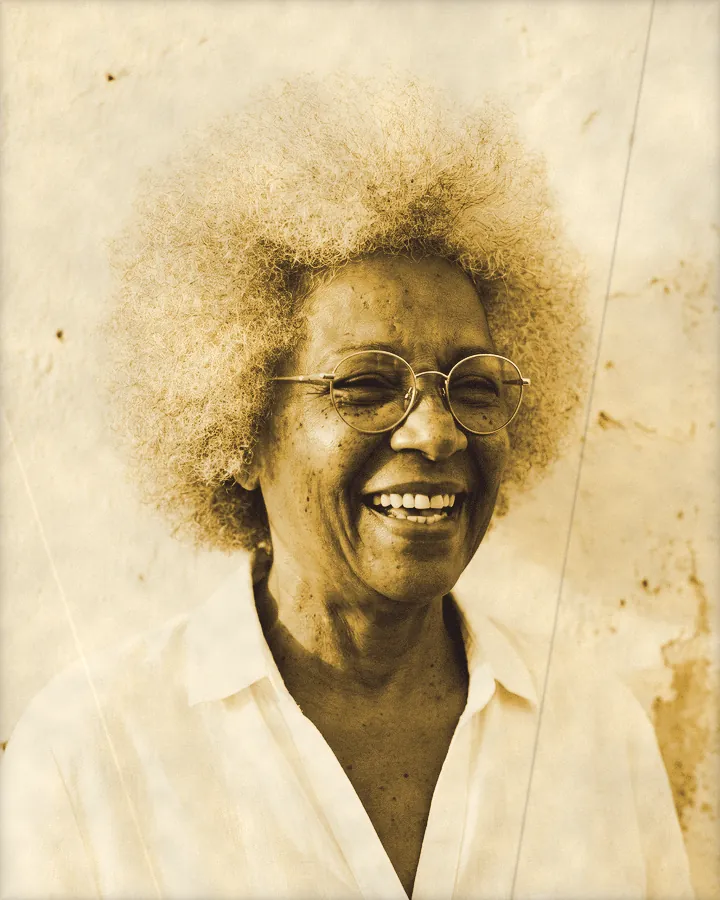 Portrait of a laughing older woman with a silver afro and gold glasses, printed for the wall