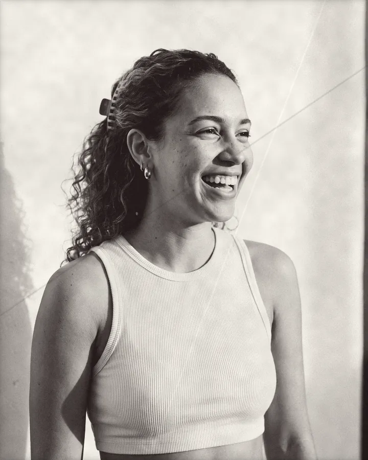 Portrait of a young woman with curls half up in a claw clip, laughing, printed for the wall