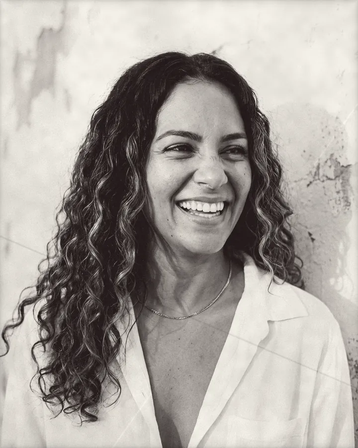 Portrait of a laughing woman with long dark curls and caramel highlights, printed for the wall