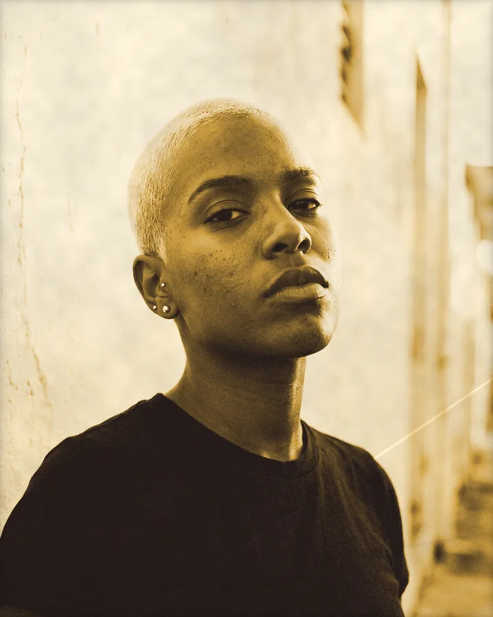 Portrait of a young woman with a platinum buzz cut and gold studs, printed for the wall