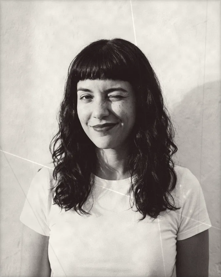 Portrait of a playful woman with wavy dark hair, blunt bangs and red lipstick, printed for the wall